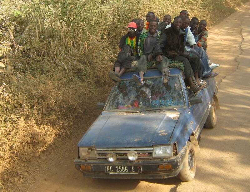 A taxi, overloaded, people sitting on the roof of the small car, Guinea