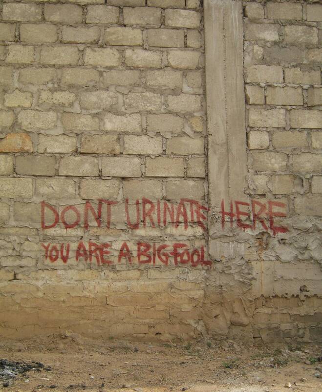 "Don't urinate here, you are a big fool" spray-painted on a cement block wall, Kumasi, Ghana